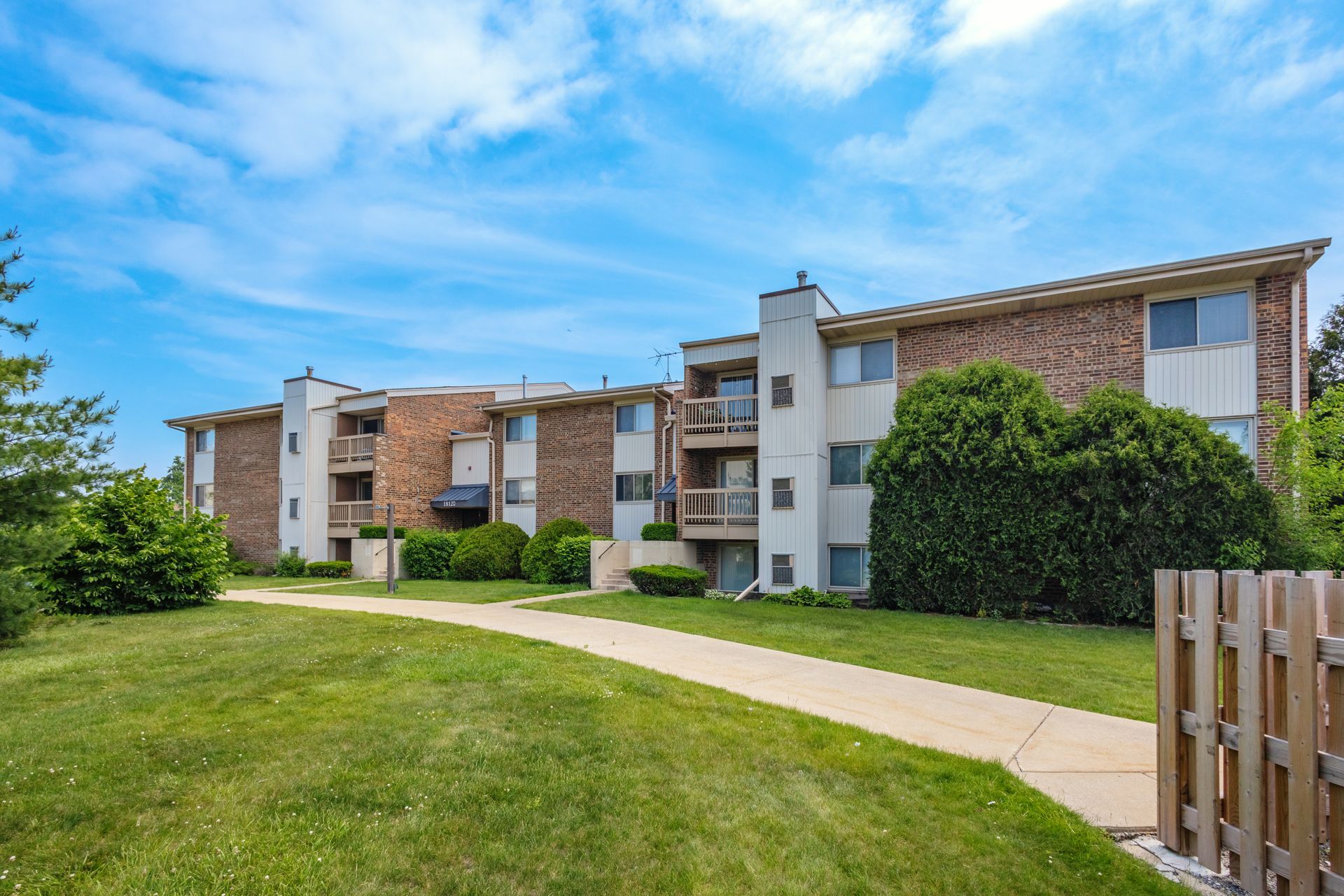 Stainless steel refrigerator in white kitchen with island, range, and cabinets.