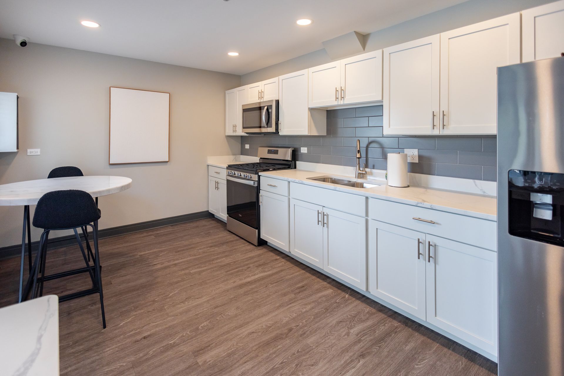 Hotel bedroom with a large bed, brown walls, and artwork. A bathroom is visible in the doorway.
