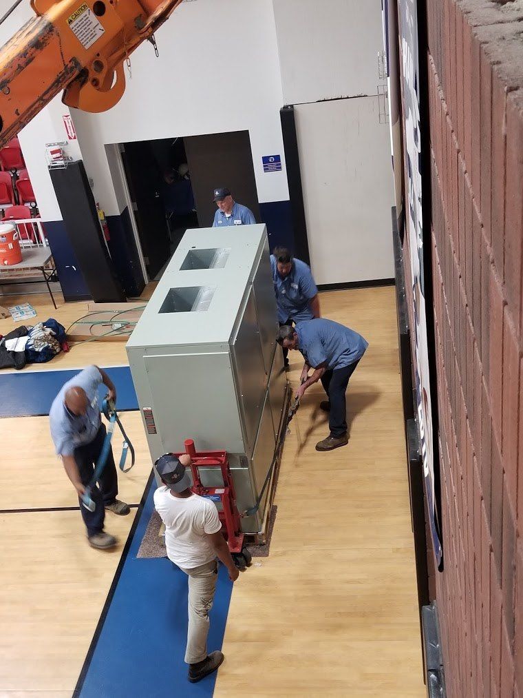 A group of men are moving a large box in a gym.