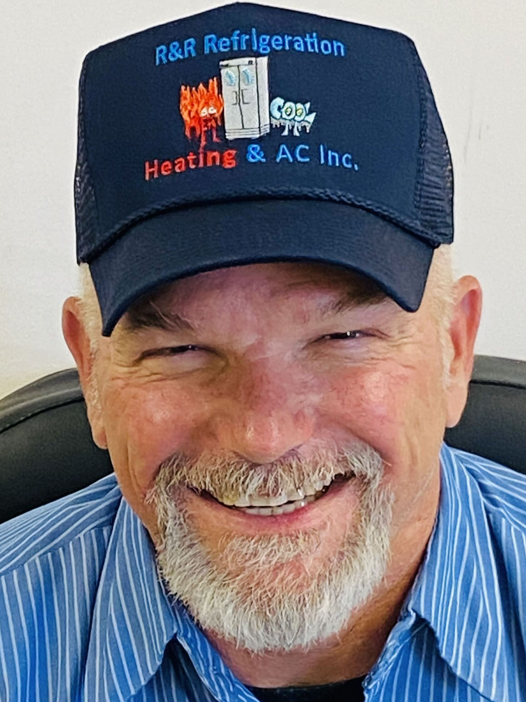 A man with a beard is wearing a hat and smiling.