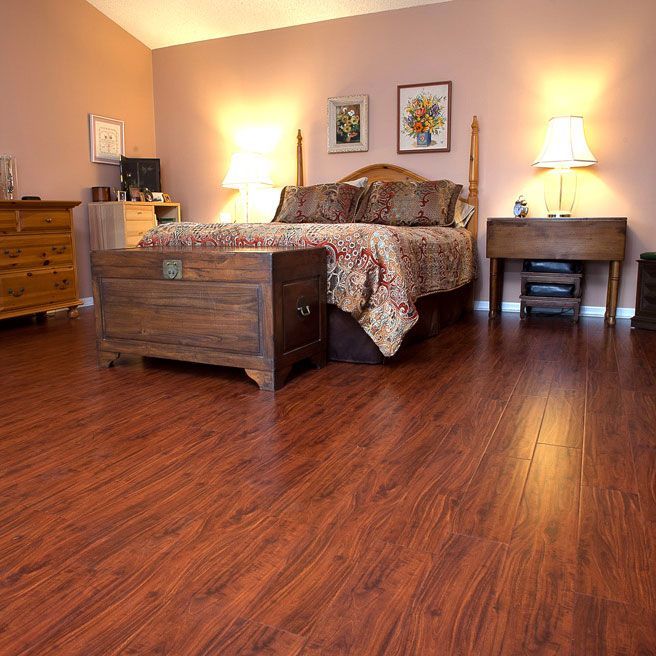 Bedroom with wooden floor, bed, chest, nightstands, and two lamps; walls are light pink.
