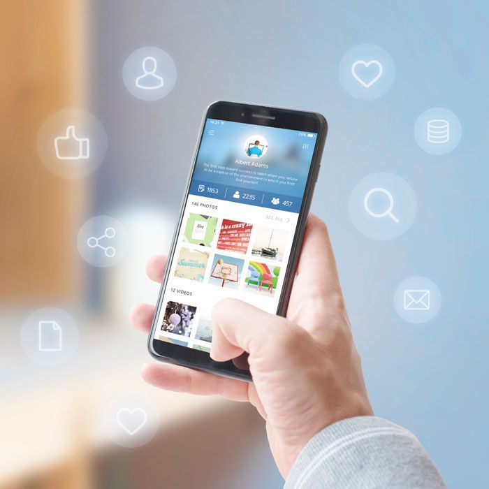 Hand holding a smartphone displaying a social media feed with floating icons.