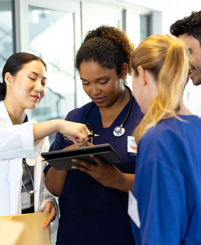 Medical team reviews patient information on a tablet in a brightly lit hallway.