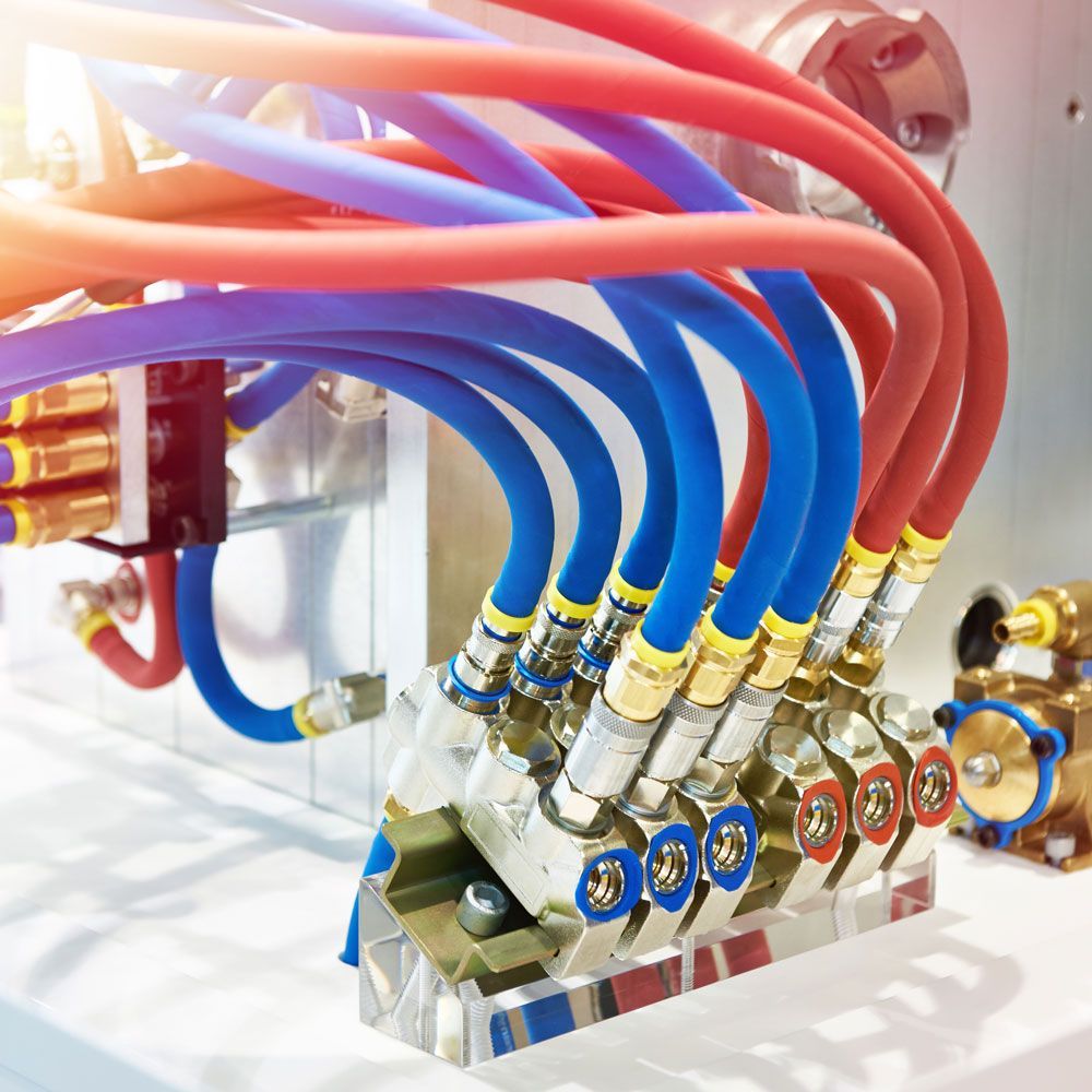 Close-up of industrial hydraulic hoses and connectors in red, blue, and purple.