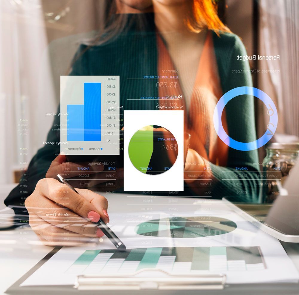 Woman analyzing financial data, charts and graphs, with laptop and tablet on desk.