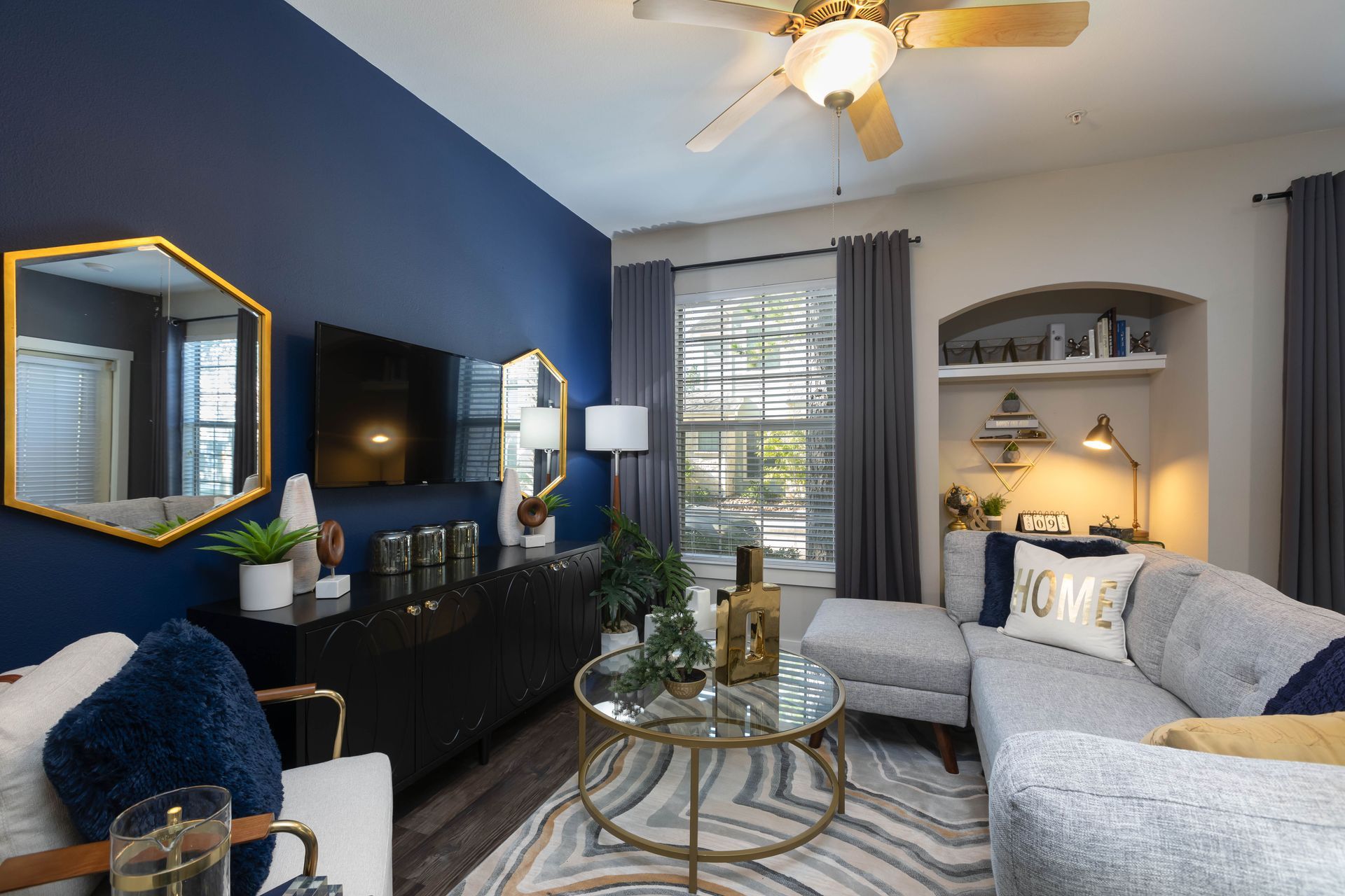 A living room with a couch , coffee table , television and ceiling fan.