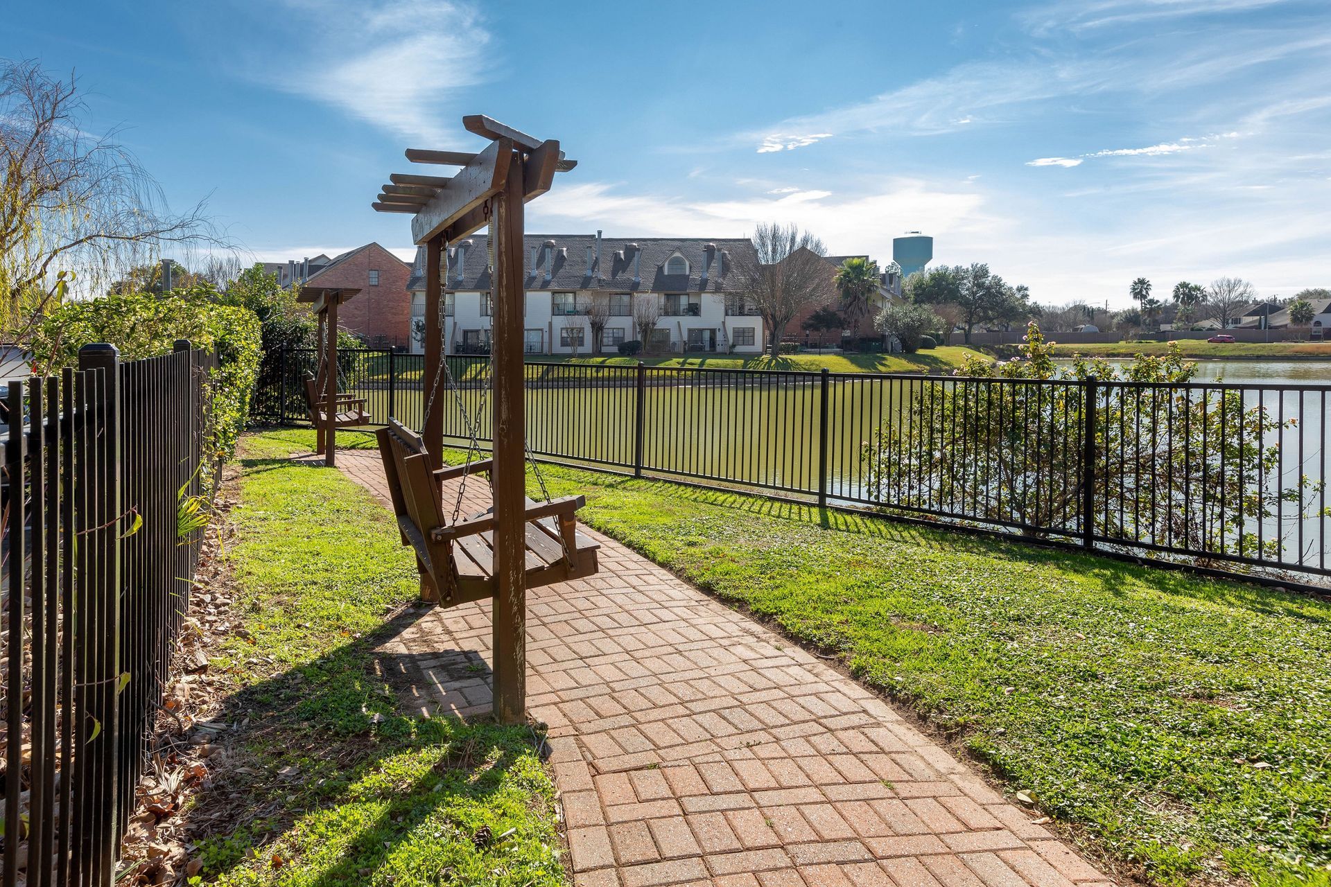 A wooden bench is sitting on a brick walkway next to a lake.
