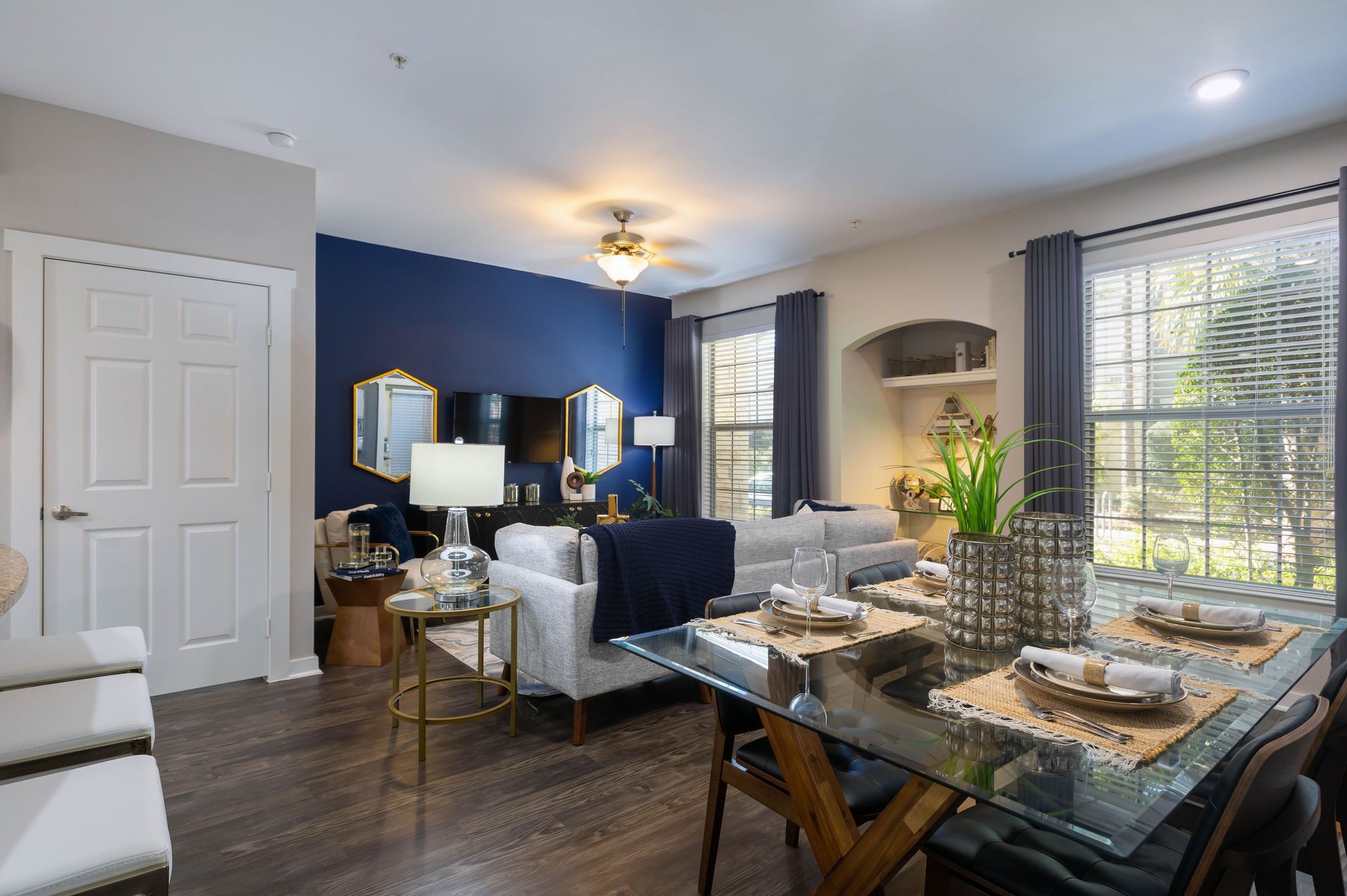 A living room with a dining table and chairs and a blue wall.