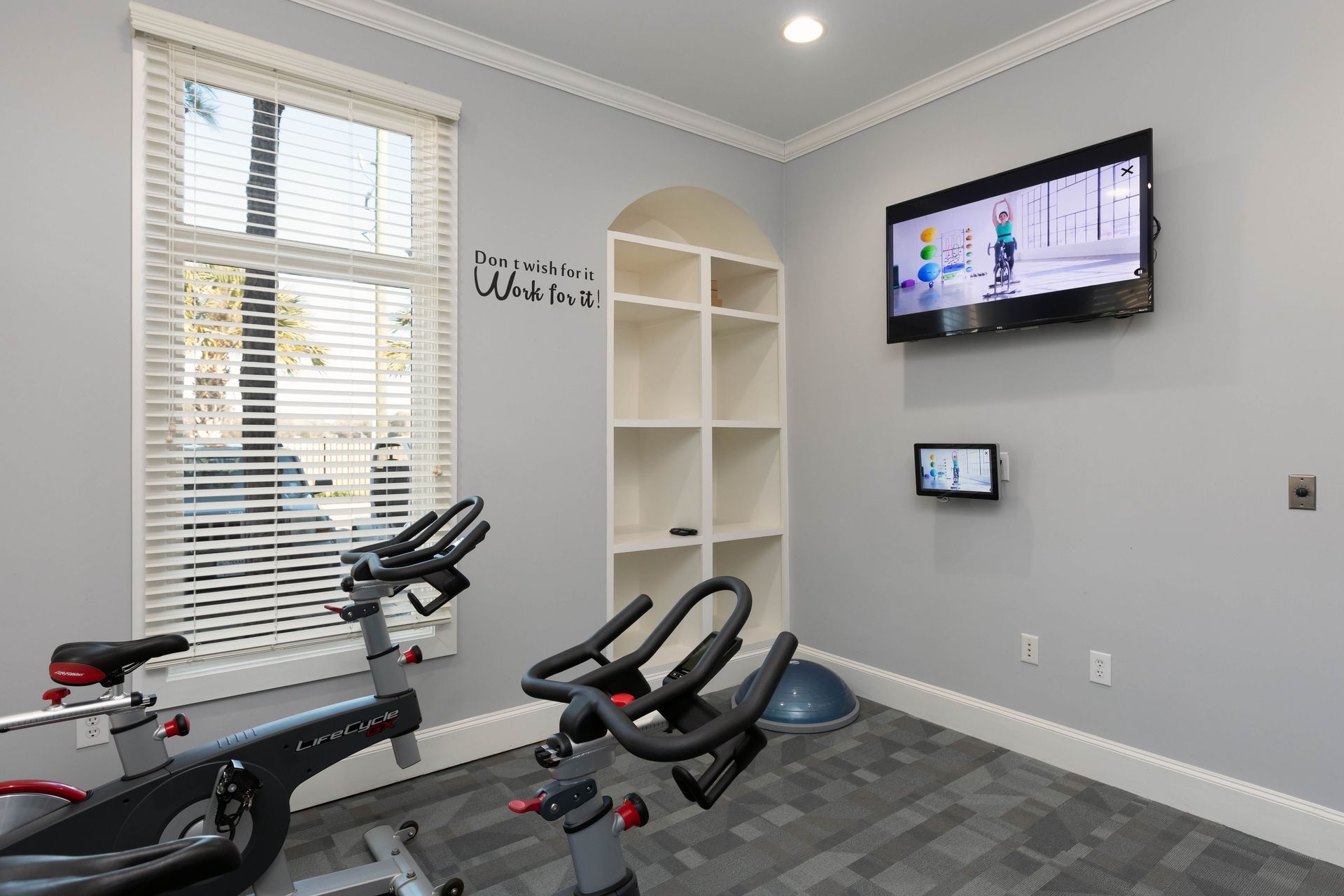 A gym with exercise bikes and a television on the wall.