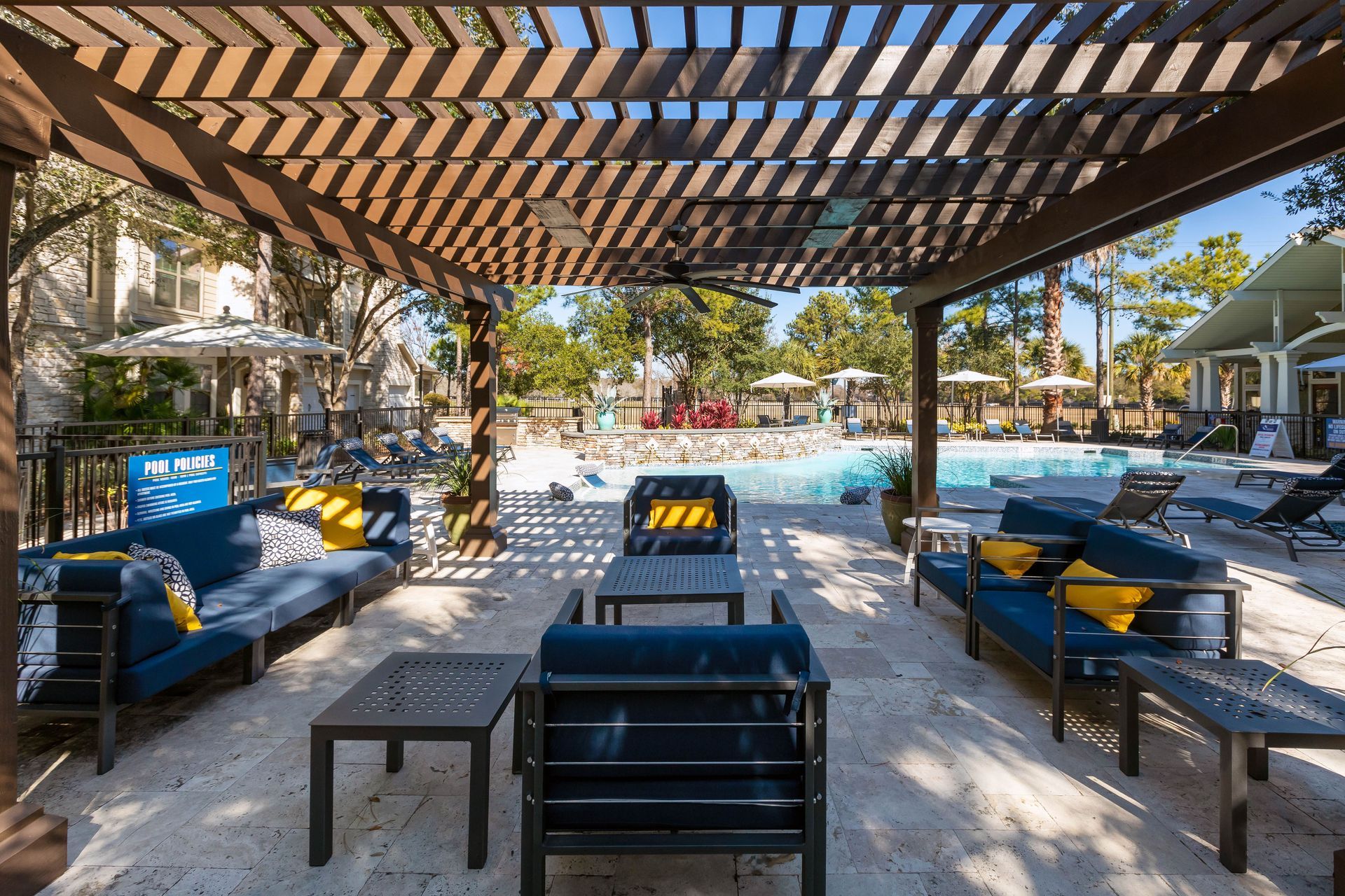 There are a lot of chairs and tables under a pergola.