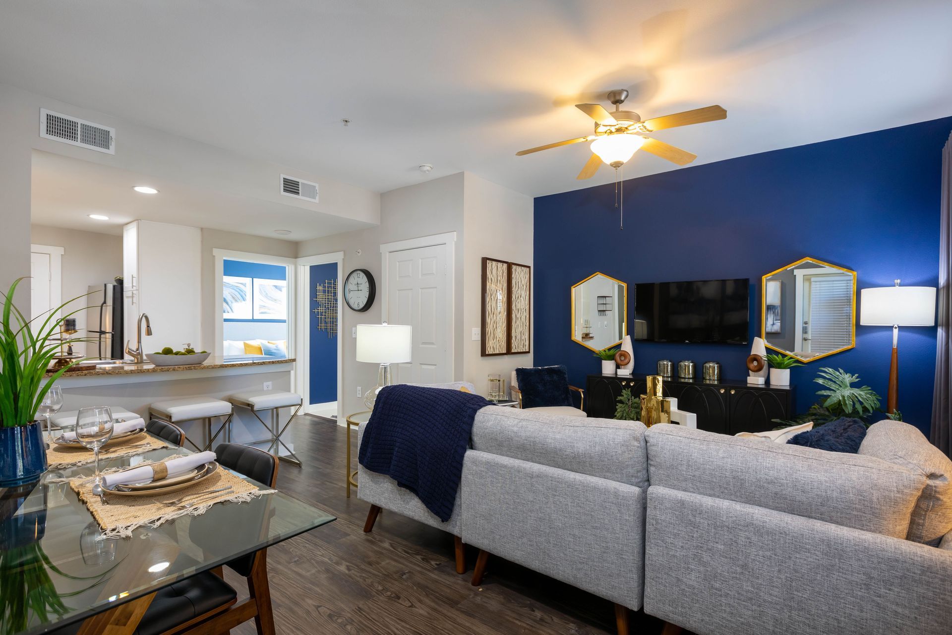 A living room with a couch , table , television and ceiling fan.