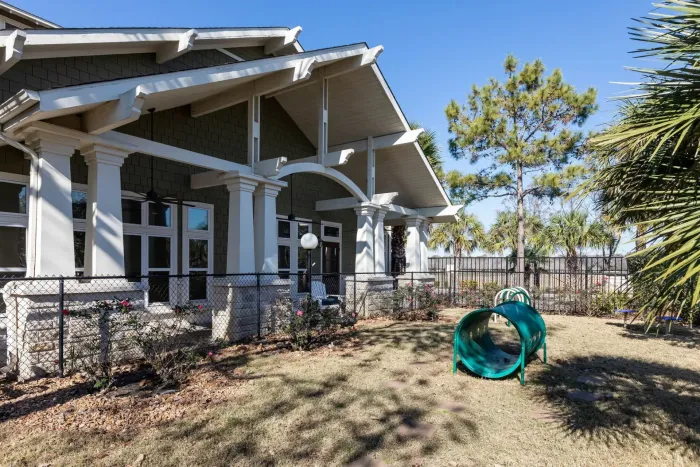 A large house with a dog park in front of it.