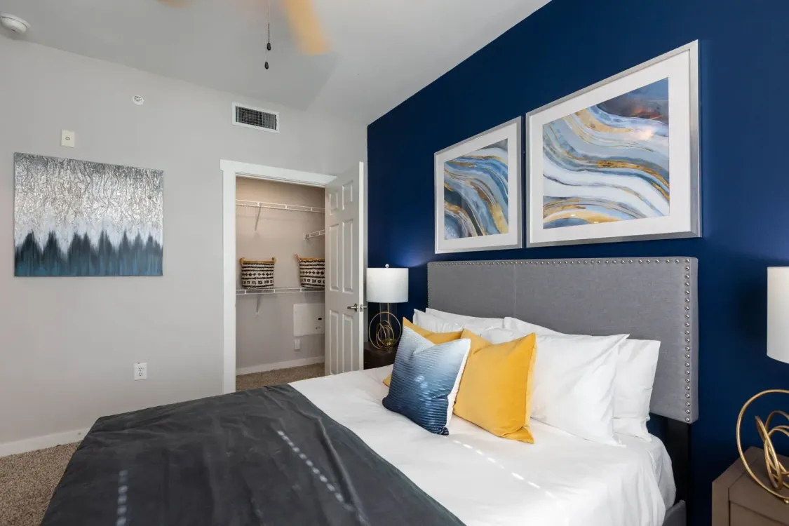 A bedroom with a bed , nightstand , lamps , and blue walls.