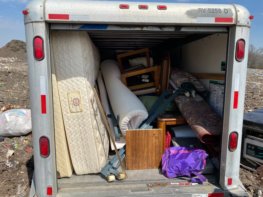 An open moving truck filled with furniture and belongings, likely for disposal.