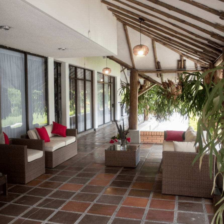 Una sala de estar con muebles de mimbre y almohadas rojas