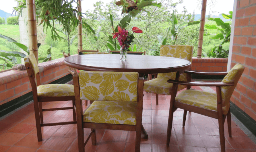 Una mesa y sillas en un balcón con un jarrón de flores.