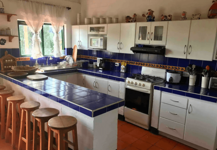 Una cocina con gabinetes blancos y encimeras de azulejos azules