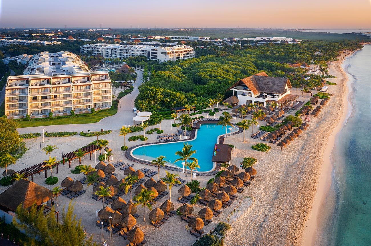 Una vista aérea de un resort de playa con una gran piscina y sombrillas.