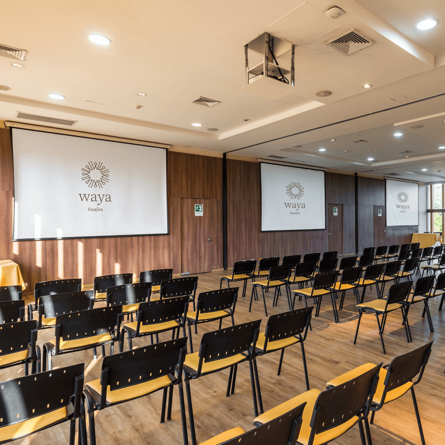 Una gran sala con hileras de sillas y una pantalla de proyección.
