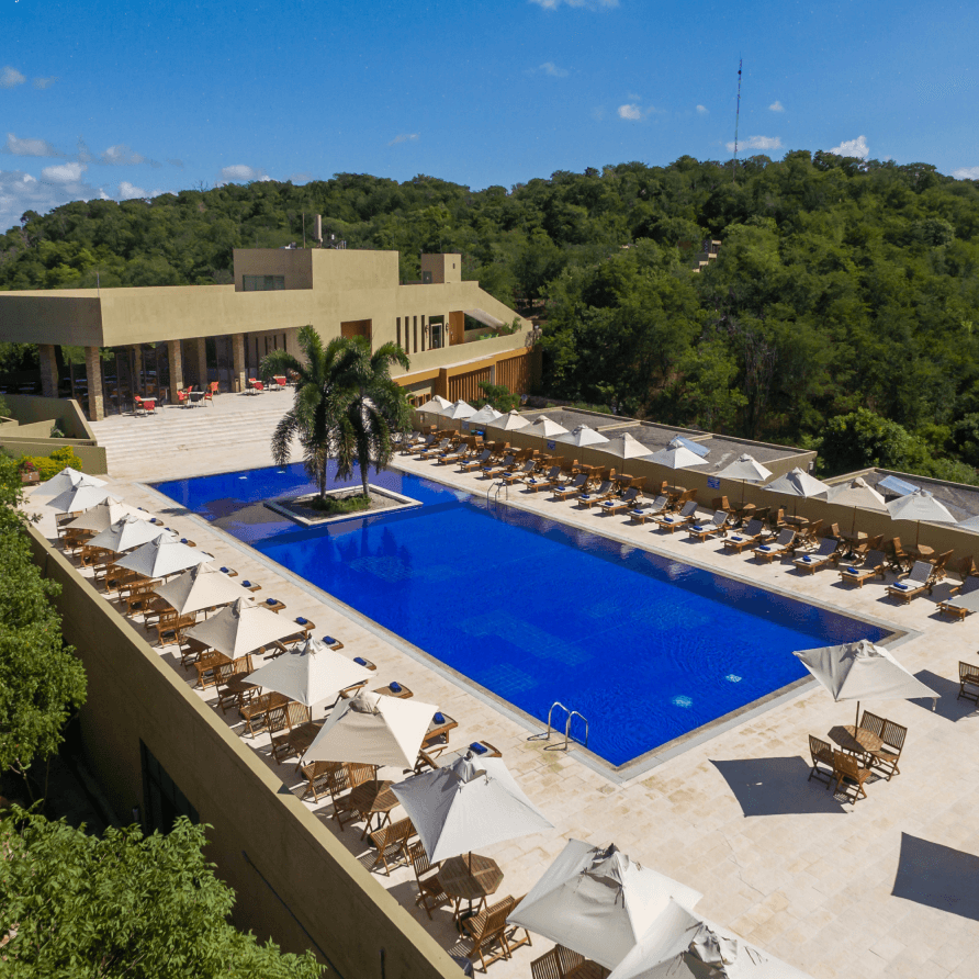Una vista aérea de una gran piscina rodeada de sillas y sombrillas