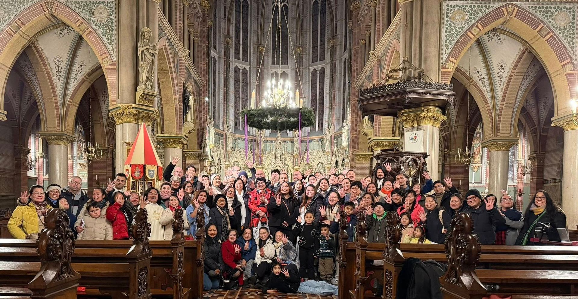 Large group of people pose inside a decorated church.