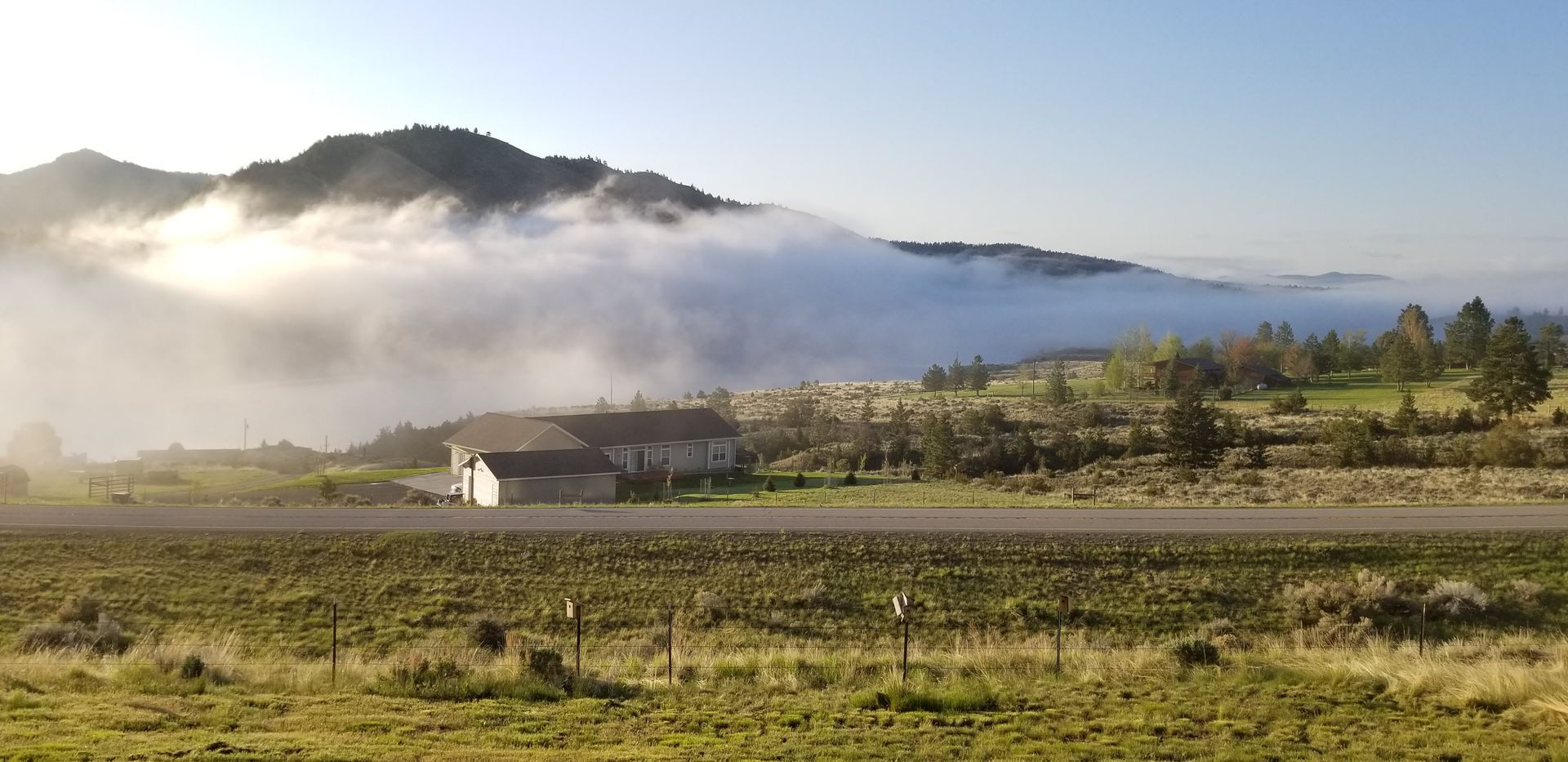 Mountain landscape with clouds over a house and fields.