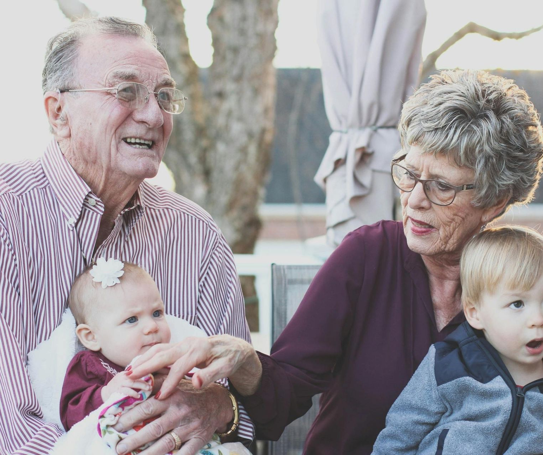An elderly couple is sitting at a table talking to a woman.