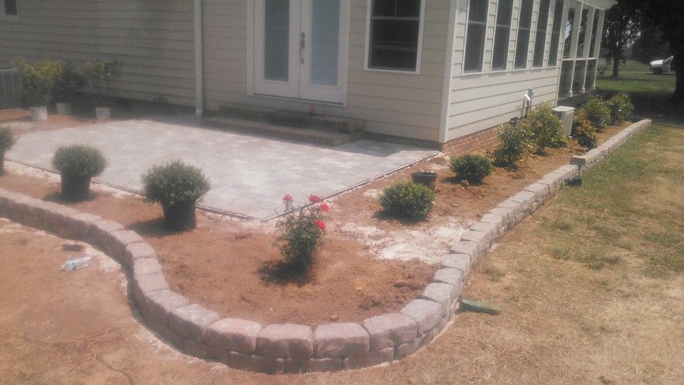 A house with a patio and a garden in front of it.
