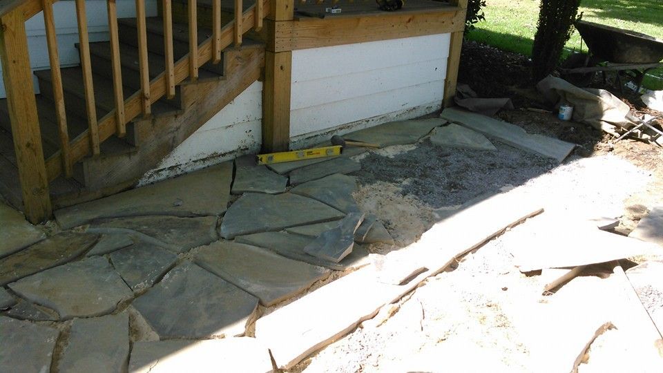 A yellow level is on the ground next to a stone walkway