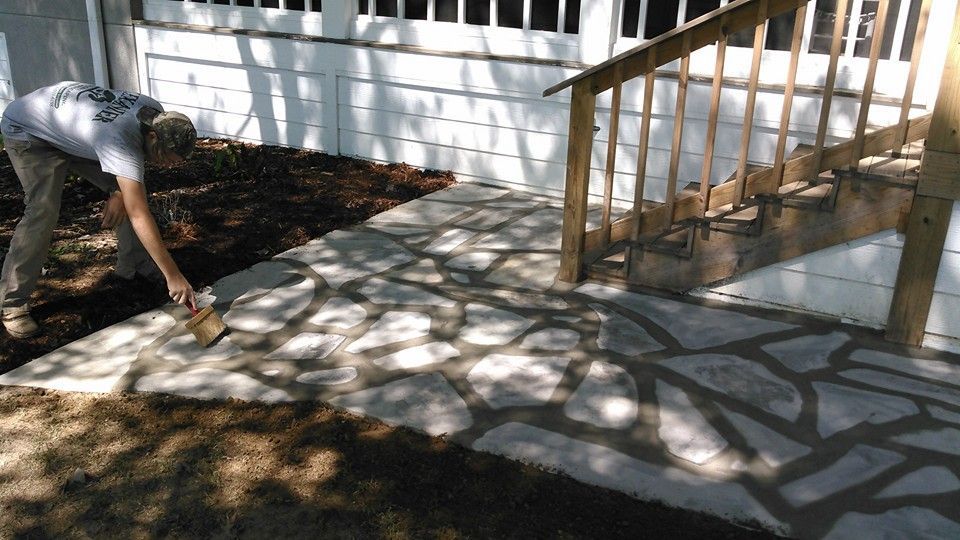 A man is working on a stone walkway in front of a house.