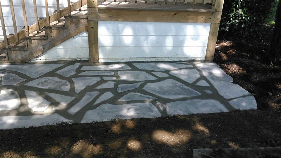 A stone patio with a wooden deck in the background