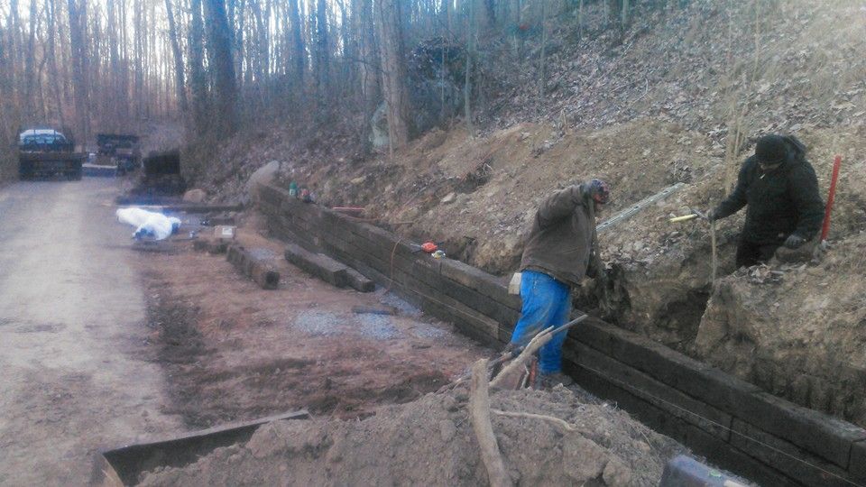 A couple of men are working on a dirt road.