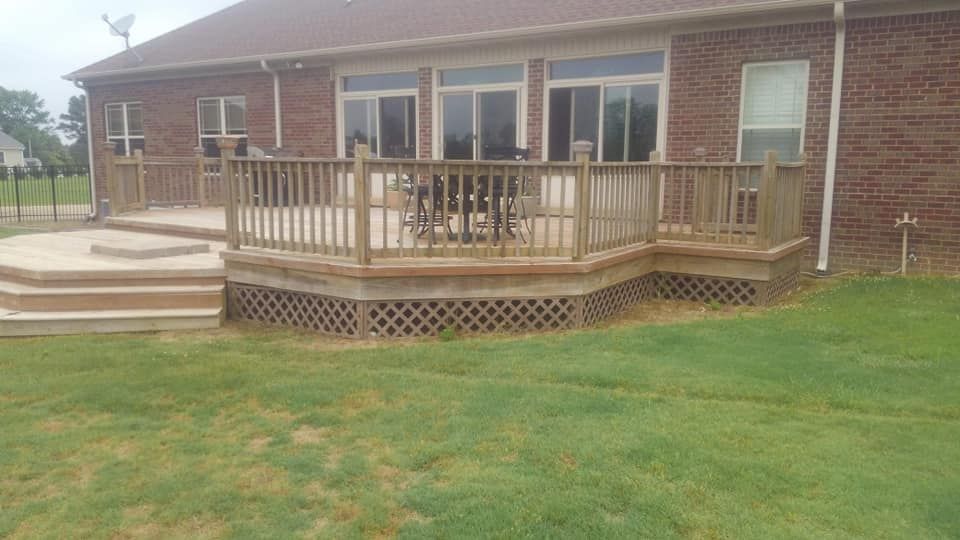 There is a large deck in front of a brick house.