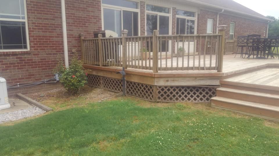 A wooden deck with stairs is in front of a brick house.