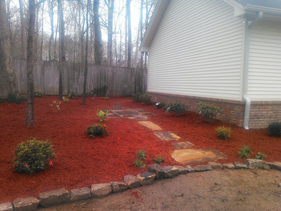 A house with a walkway leading to it surrounded by red mulch.