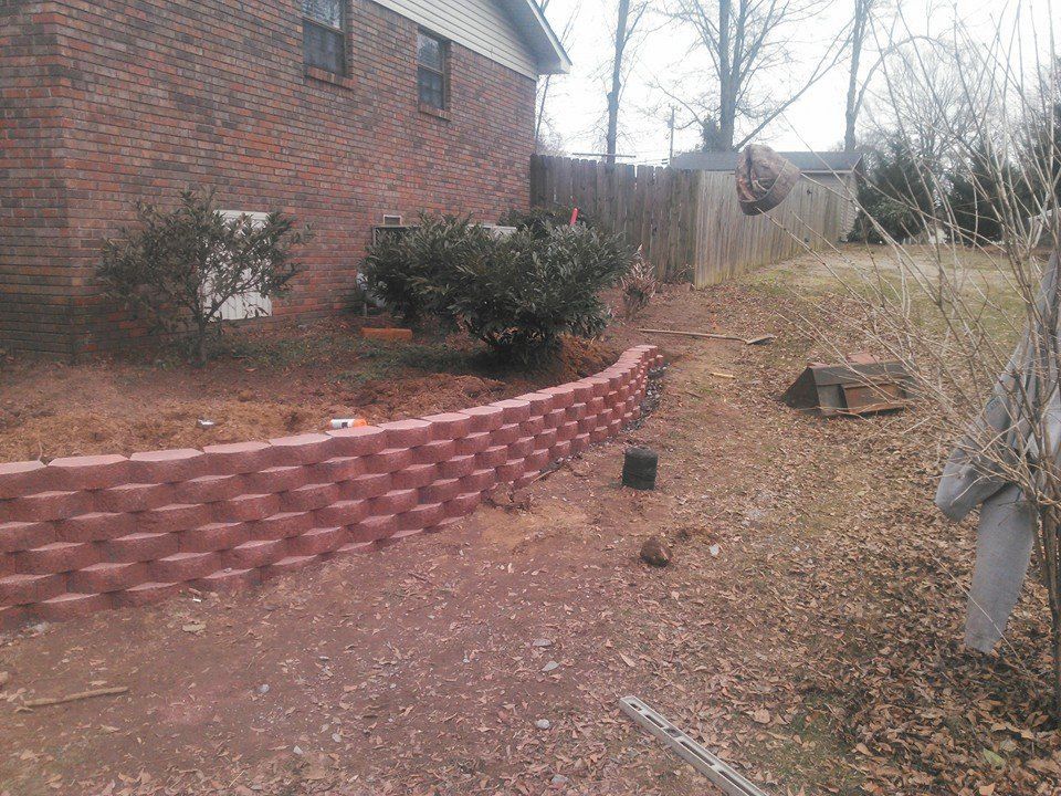 A brick wall is being built in front of a brick house.