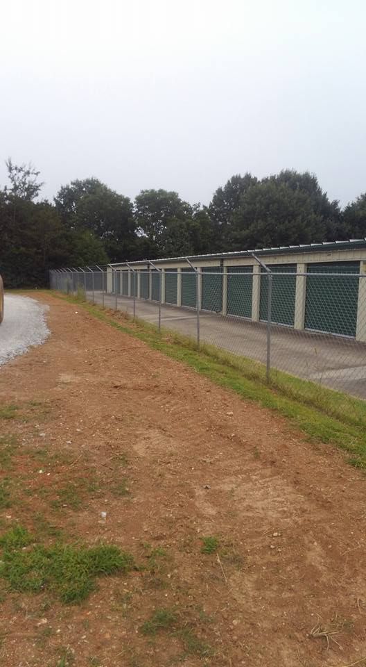 A row of storage units behind a chain link fence.
