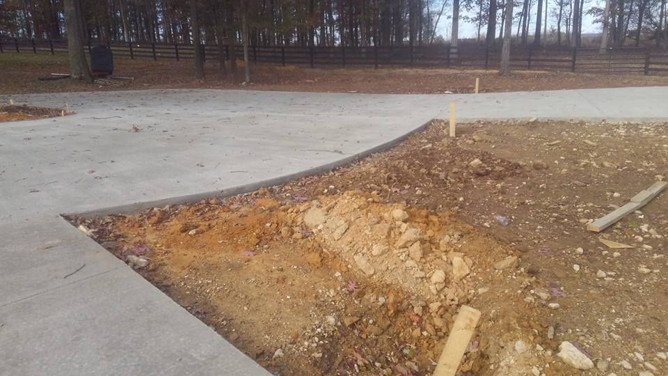 A concrete walkway is being built in a park with trees in the background.