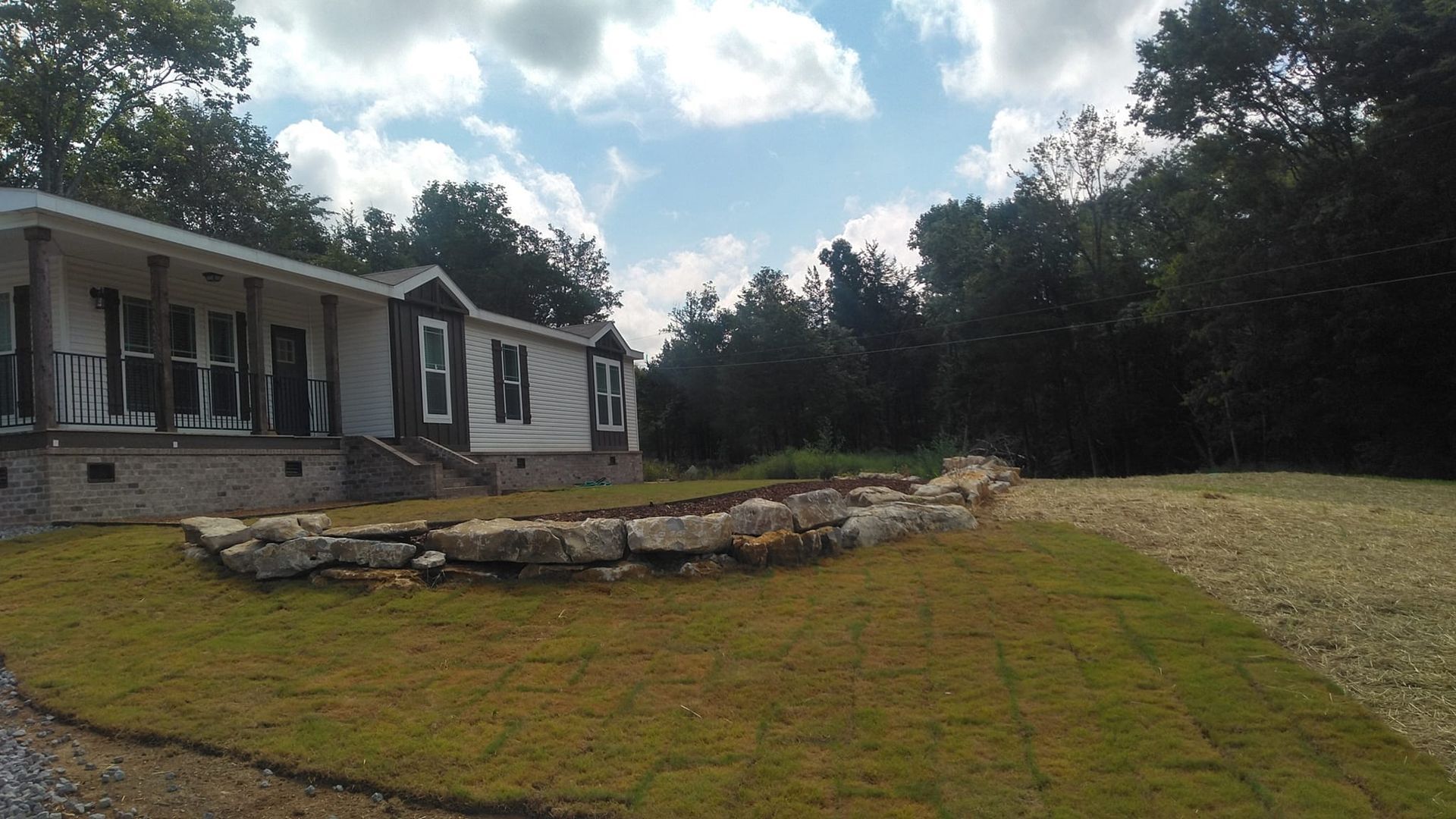A mobile home is sitting in the middle of a lush green field.