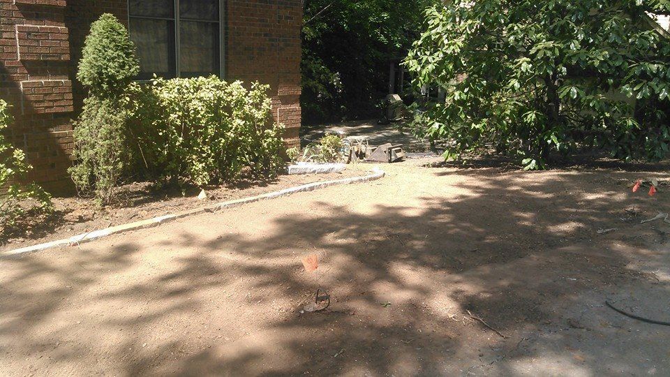 A brick house with a dirt driveway in front of it