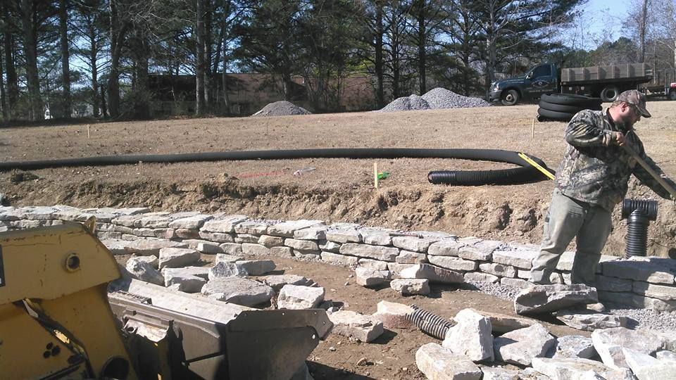 A man is standing in a field with a shovel in his hand