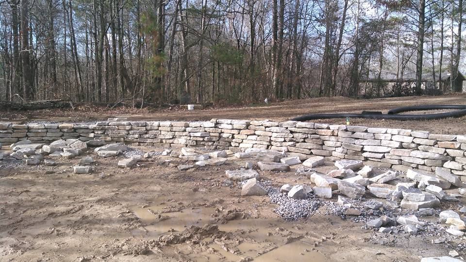 A pile of rocks in a field with trees in the background