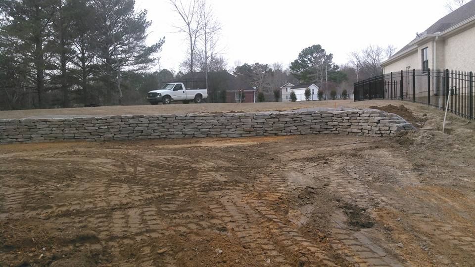 A white truck is parked in a dirt field in front of a house.