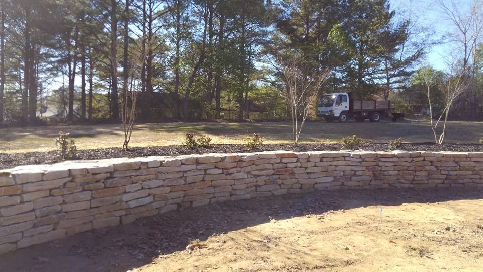 A truck is parked in front of a stone wall.