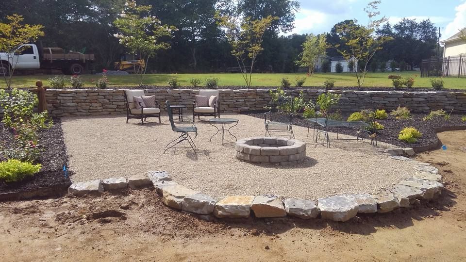 A fire pit is in the middle of a patio with chairs and tables.