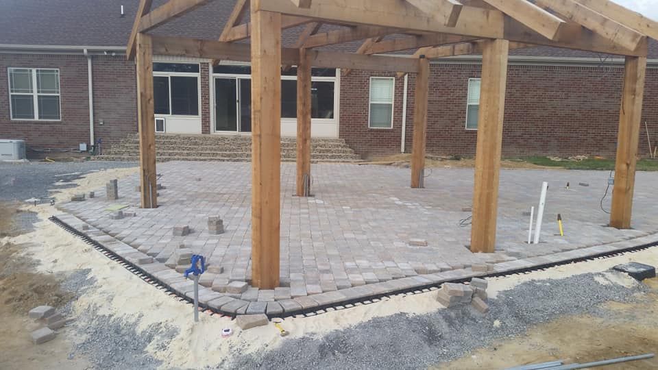 A wooden pergola is being built in front of a brick house.