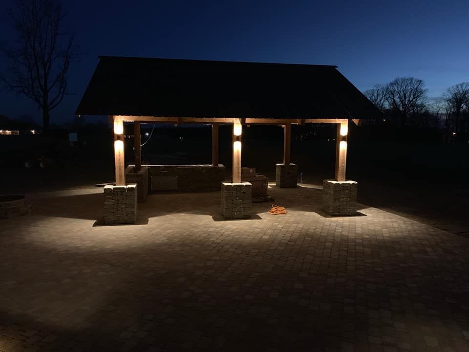 A gazebo is lit up at night in a park.