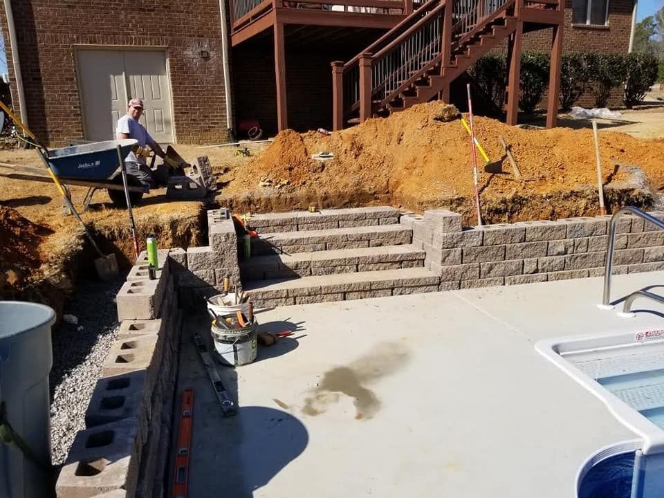 A man is loading dirt into a wheelbarrow in front of a house.