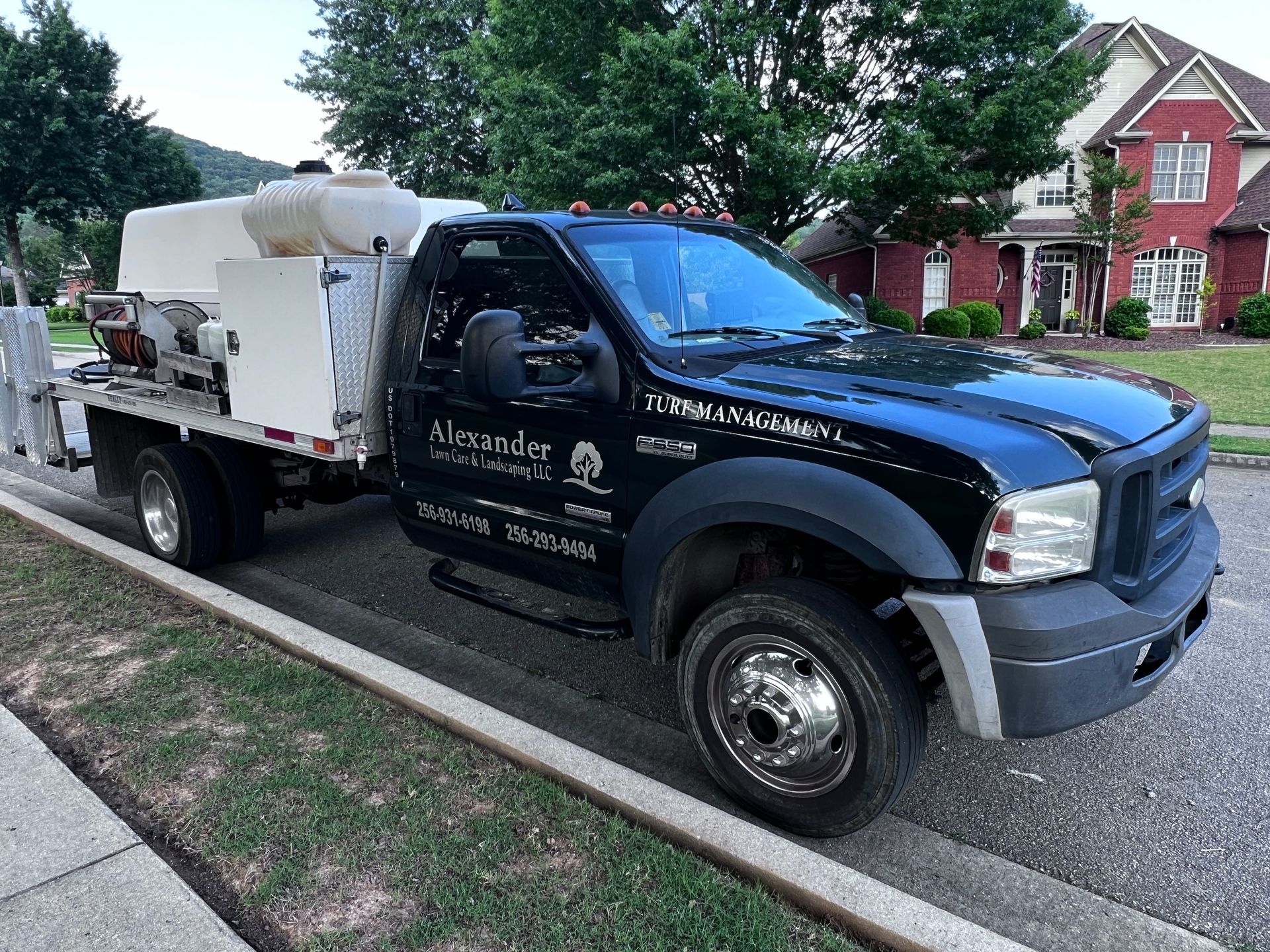 A black and white truck is parked on the side of the road in front of a house.