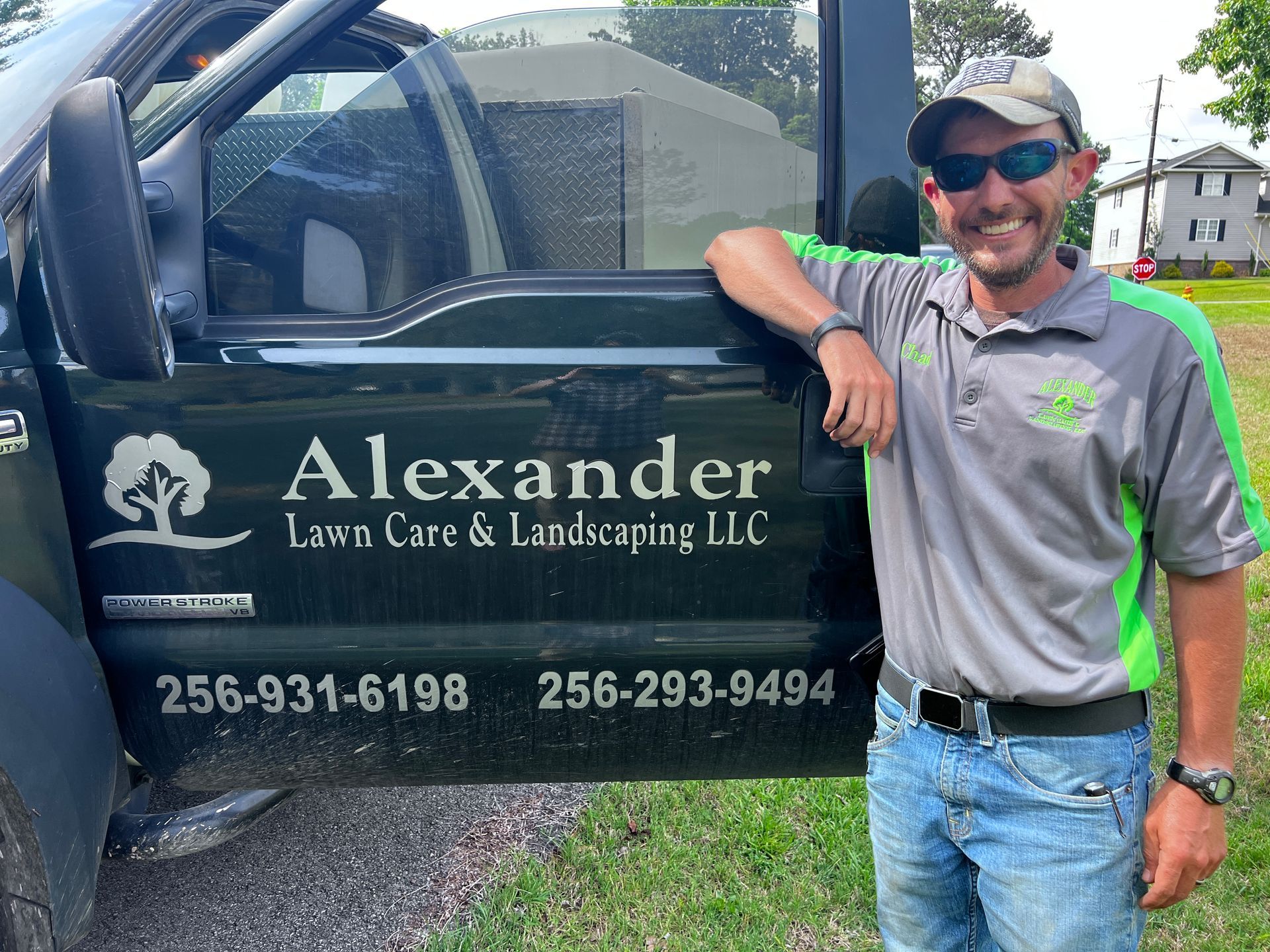 A man is standing in front of a truck that says alexander lawn care and landscaping llc.